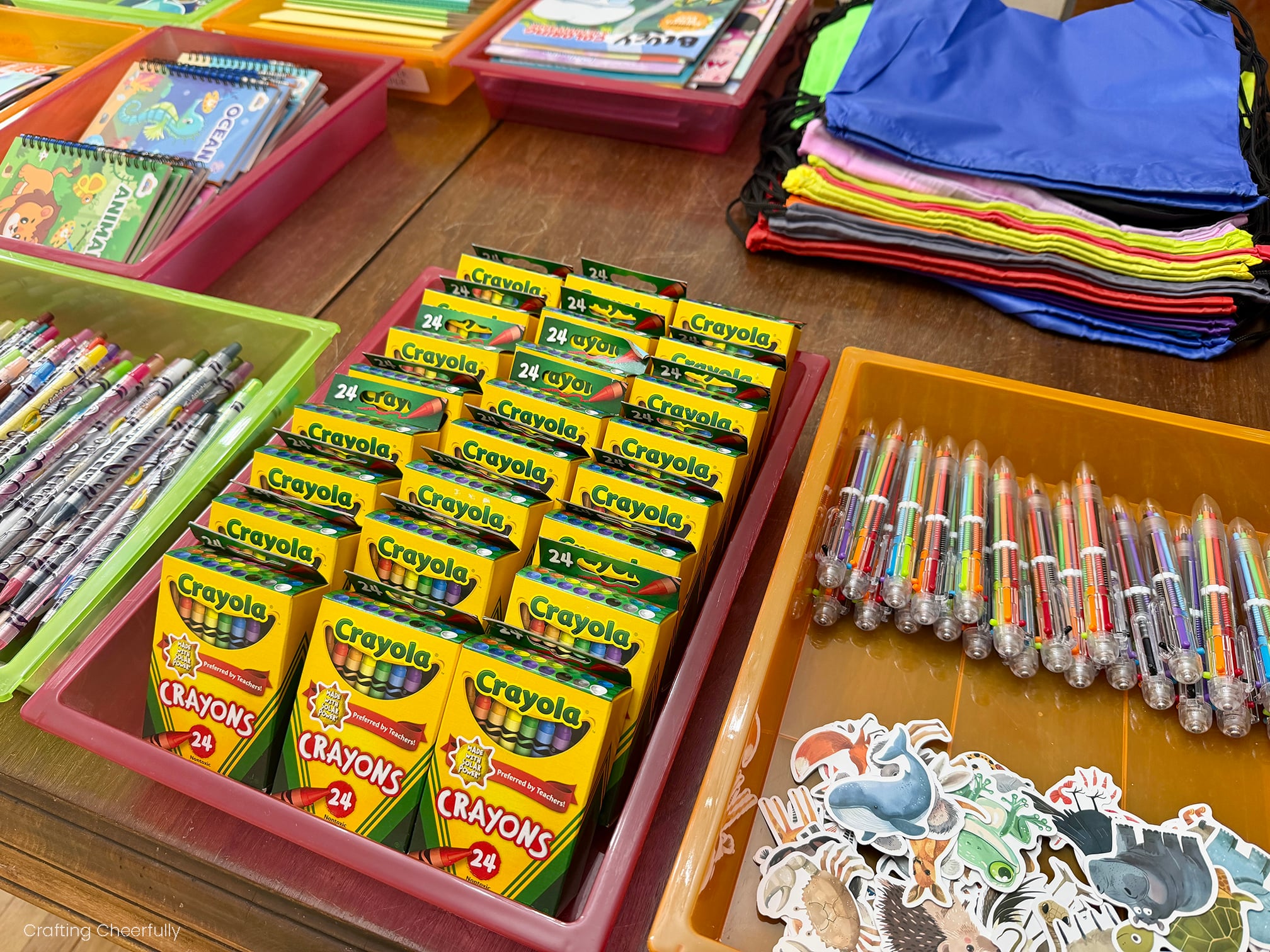 Trays of Crayola crayons and other coloring supplies lay in trays on a table.