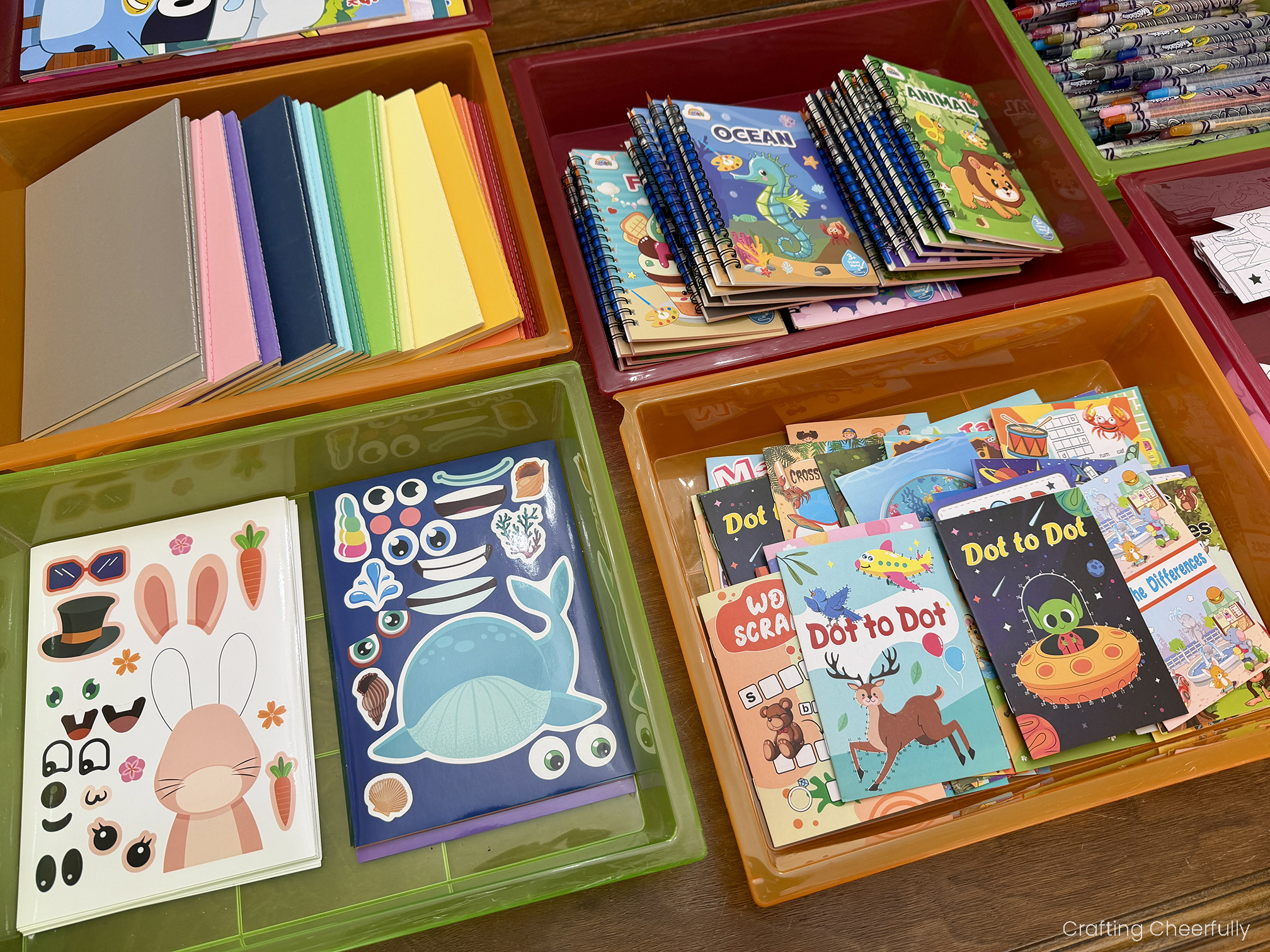 Sticker pages, notepads, and activity books in trays on a table.