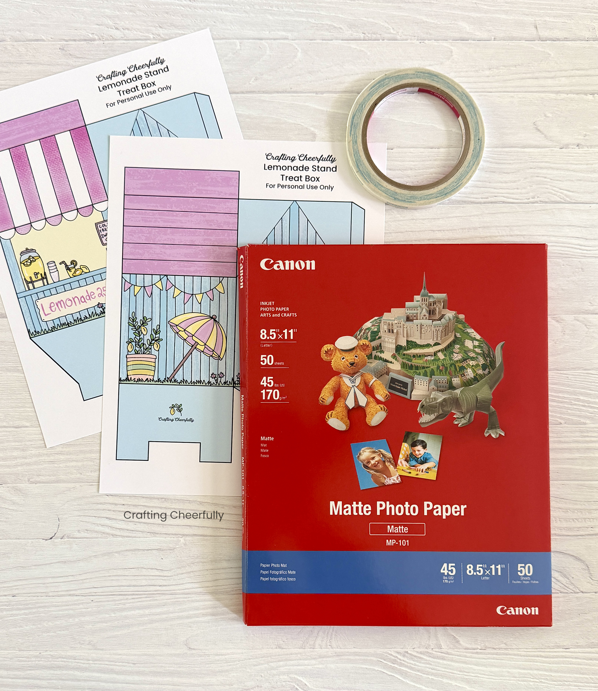 Treat box printables lay next to a package of matte photo paper and a roll of double-sided tape.