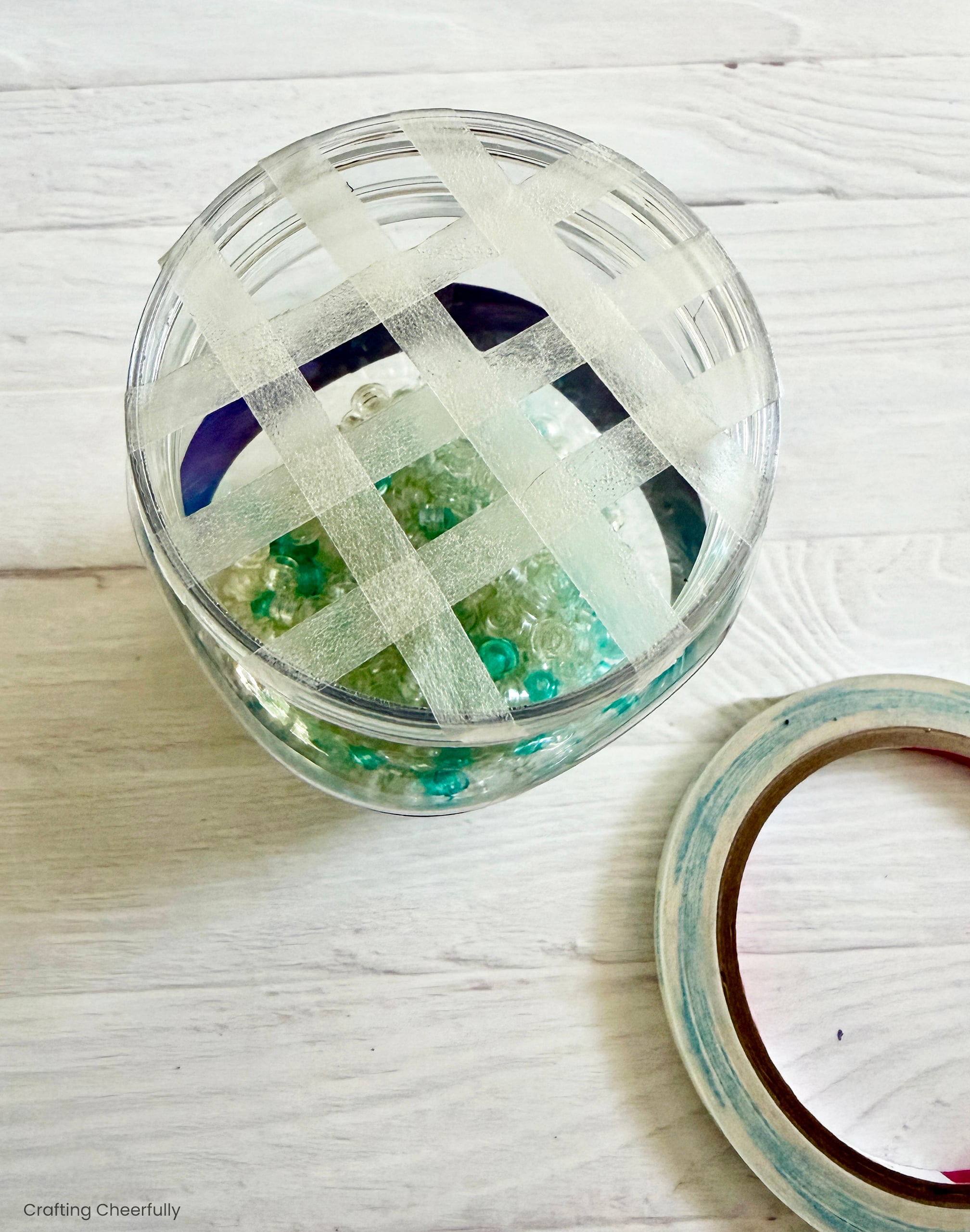 Thin strips of double-sided tape are placed in a grid over the top of the mason jar.