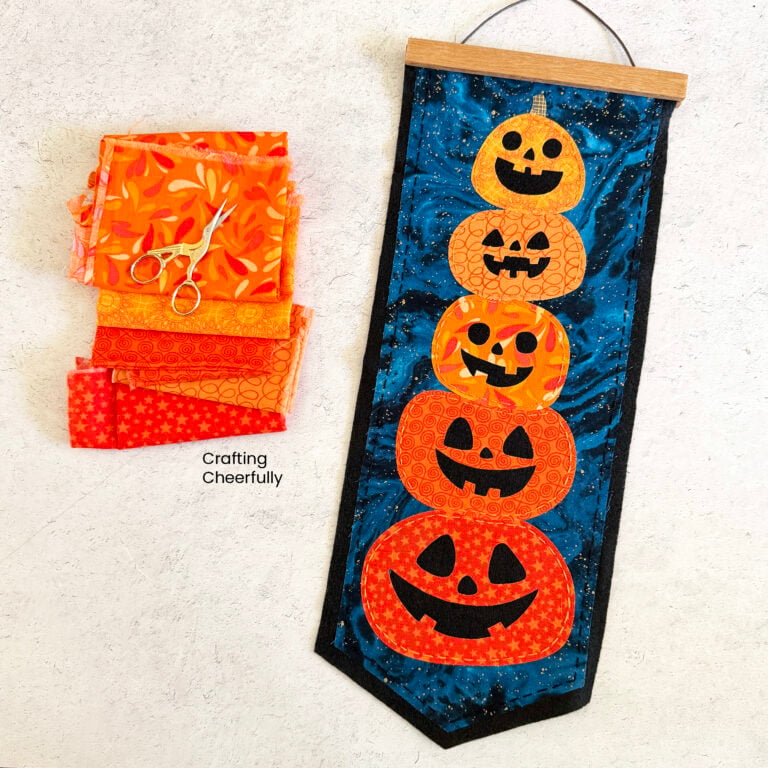 Halloween pumpkin pennant lays next to scraps of orange fabric.