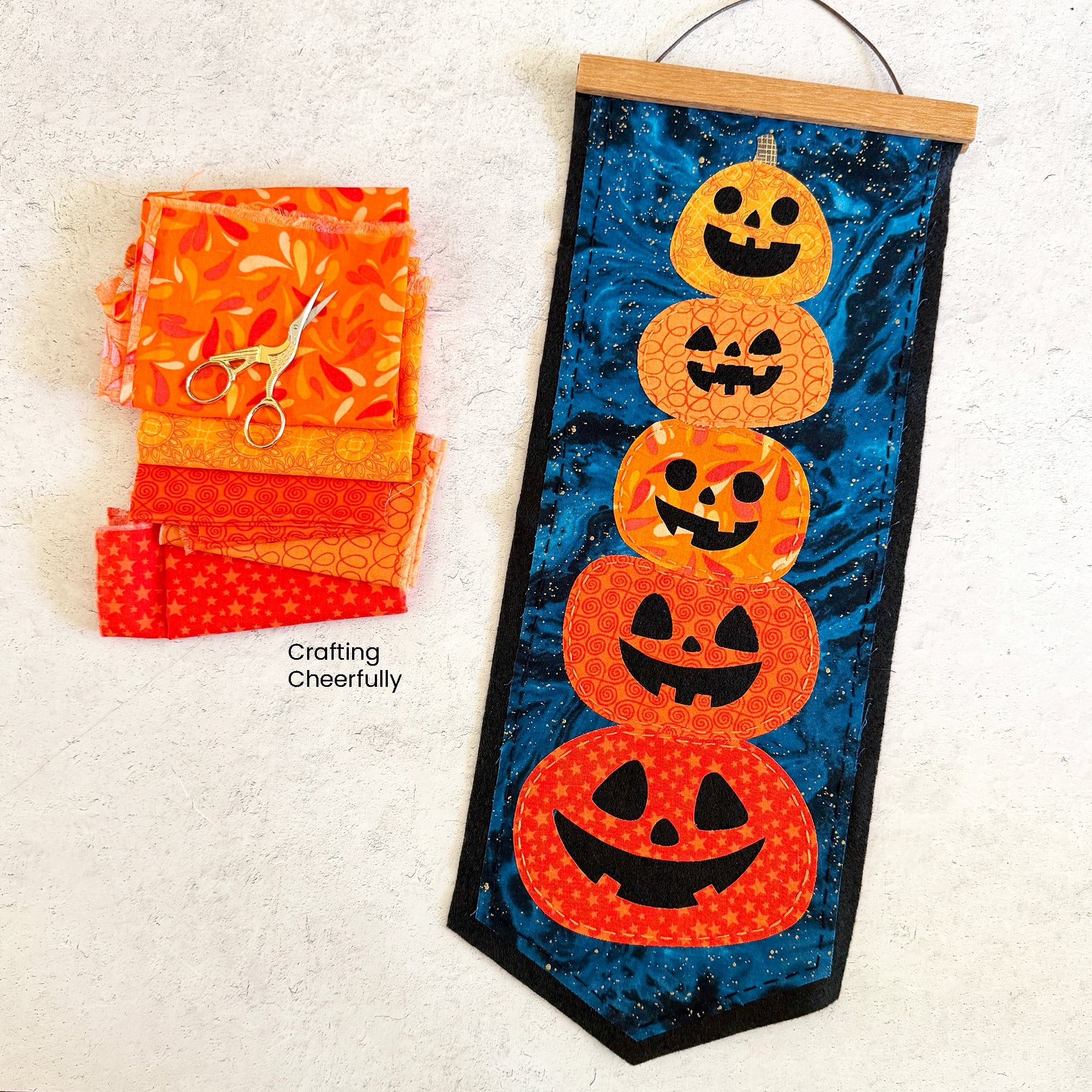 Halloween pumpkin pennant lays next to scraps of orange fabric.