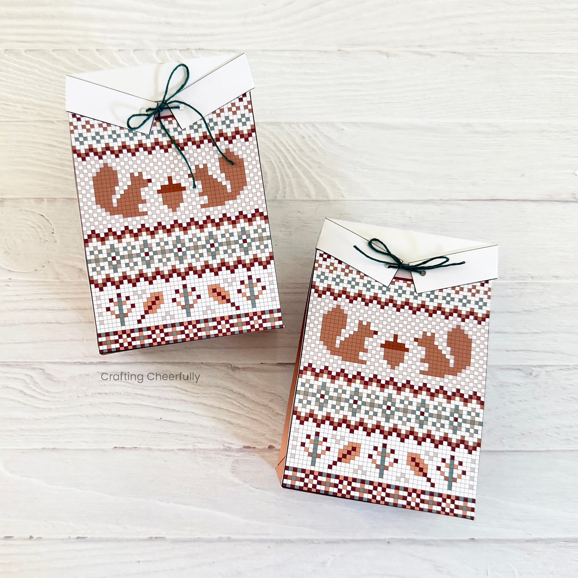 Two fall sweater treat boxes lay on a white wood table.