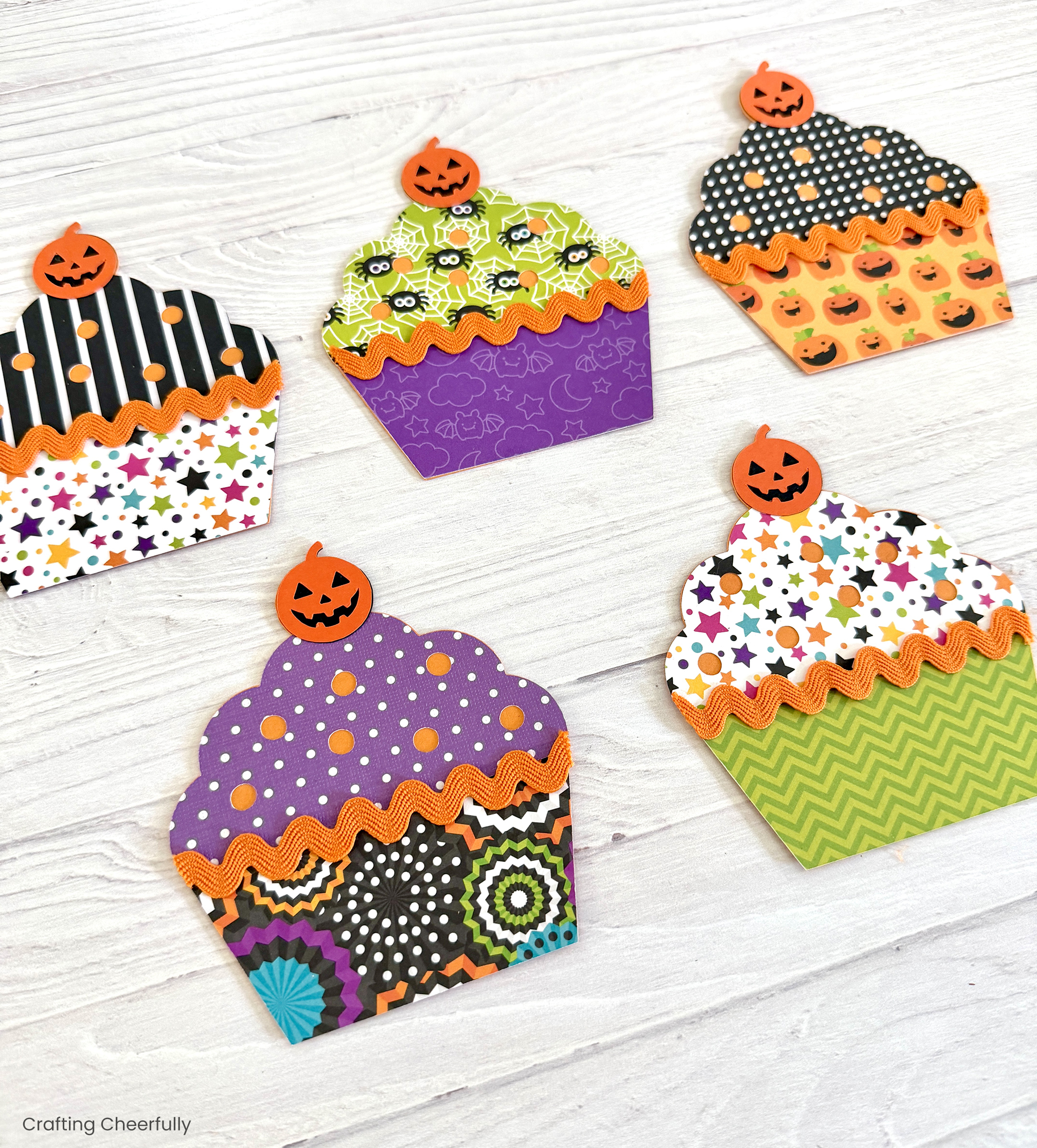 Colorful and fun paper cupcakes with jack-o'-lantern cherries on top.