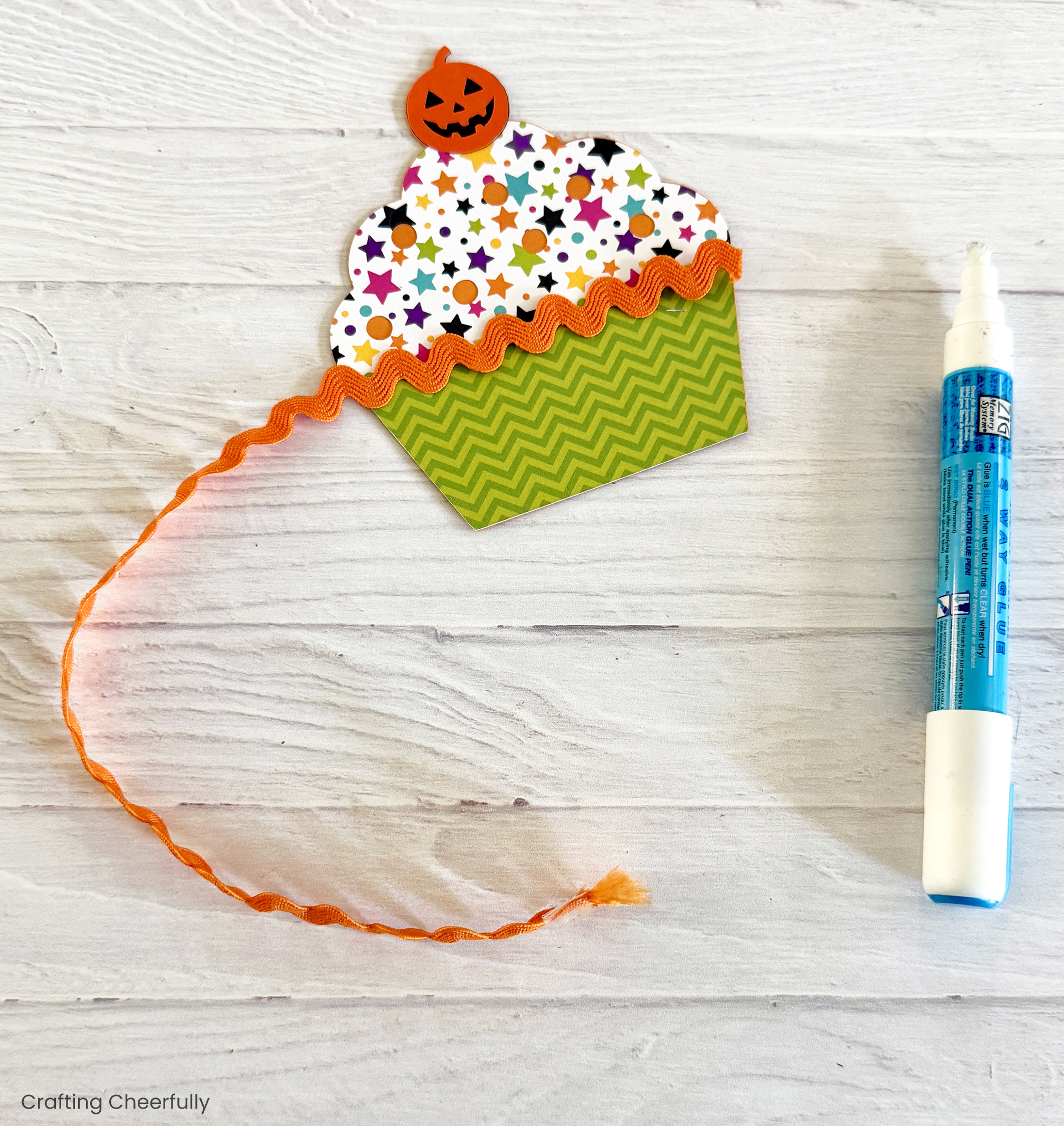 Orange ric rac is applied to the paper cupcake with a glue pen.