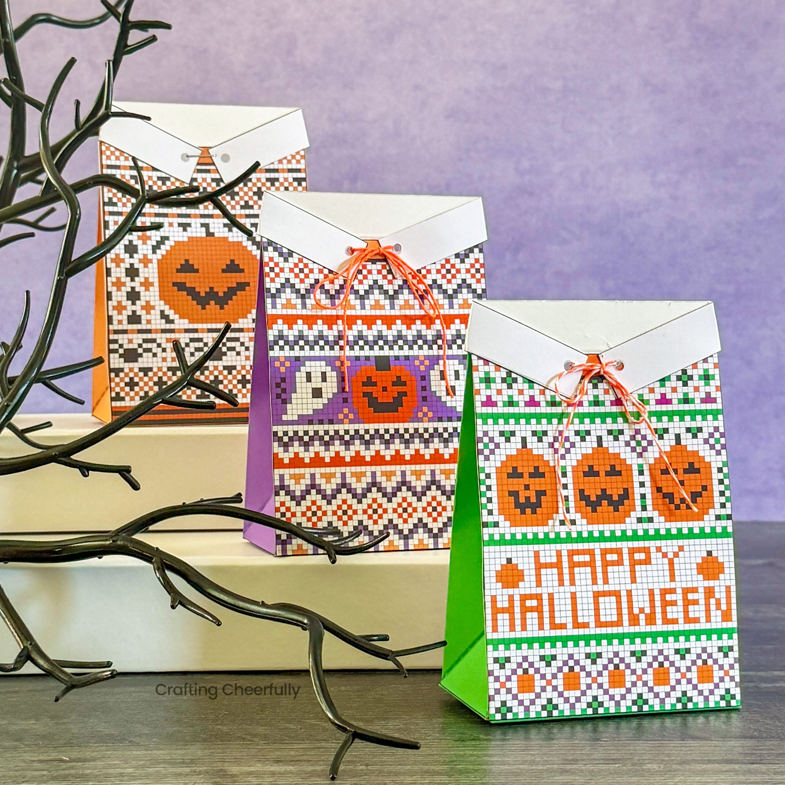 Three Halloween treat boxes sit in a row designed to look like Halloween sweaters.