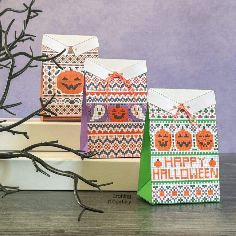 Three Halloween treat boxes sit in a row designed to look like Halloween sweaters.