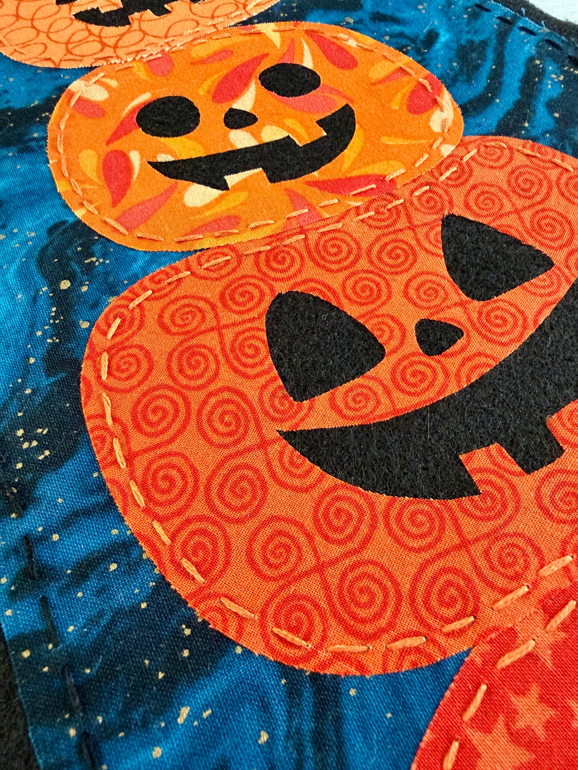 Close up of the hand stitched pumpkins on the wall hanging.