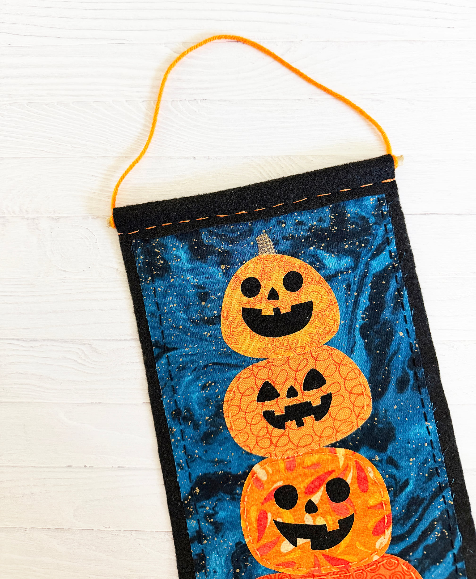 The wall hanging finished with a wooden dowel and orange yarn.